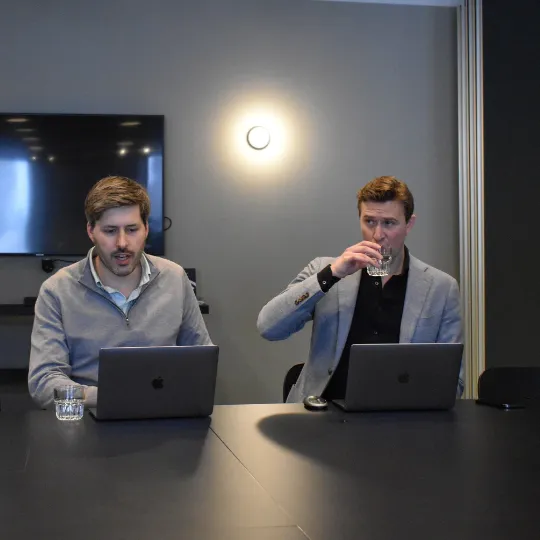 A picture of 2 men at laptops